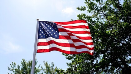 United States flag waving against green trees in clear sky  