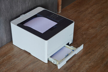 top view, side black and white laser printer sitting on a wooden floor and grey and black wall, technology, object, decor, copy space