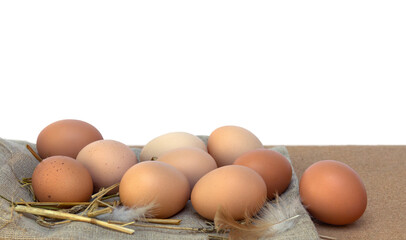 Farm eggs on burlap and straw on white background with space for text