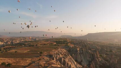 Aerial view Colorful hot air balloons rise over unique Cappadocia arid landscape at sunrise, symbolizing freedom, adventure, bucket list travel, get away, romantic escape, natural wonders