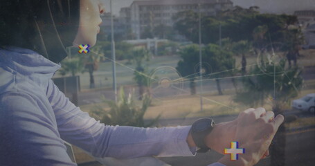 Leaning woman wearing sports shirt and smartwatch on balcony overlooking street, overlay graphics