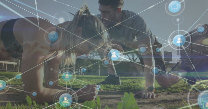 Exercising partners in athletic wear doing plank and push-up at park, with digital network overlay