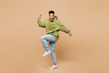 Full body young man of African American ethnicity wear green hoodie casual clothes doing winner...