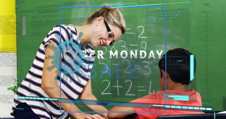 Leaning teacher pointing at green chalkboard equations while assisting boy at desk in classroom
