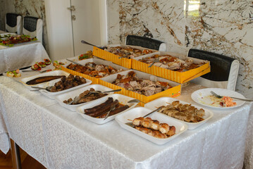 Food, salads, meat, barbecue, etc. are served on the tables, ready to eat.