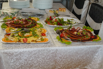Food, salads, meat, barbecue, etc. are served on the tables, ready to eat.