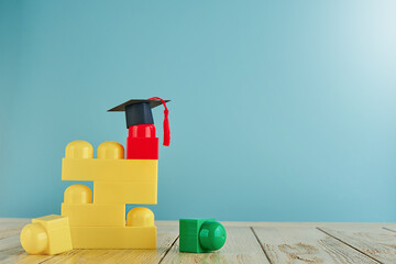 Multicolored construction cubes for children and black and masters cap or an oxford cap on blue background. Concept education, development and learning. Empty background. Back to school concept.