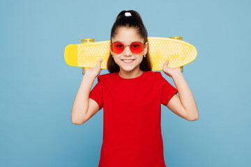 Little child kid girl 8-9 years old wear red t-shirt have fun hold in hand skateboard pennyboard on...