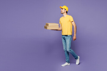 Full body young delivery guy employee man wearing yellow cap t-shirt uniform workwear work as...