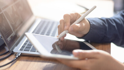 Stylus touching tablet screen next to connected laptop in creative workspace. Ideal for digital design, sketching, remote work, content creation, and online collaboration themes.