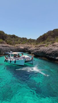 Tourist dives from anchored boat into turquoise sea in Mallorca during summer vacation, enjoying nautical tourism. Concept of summer, nautical tourism, Mediterranean vacation.