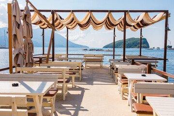 Seaside restaurant terrace with shaded canopy and panoramic island view. Summer relaxation,...