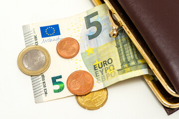 Aus einem Geldbeutel fallen einige Euro Münzen und ein Fünf-Euro-Schein