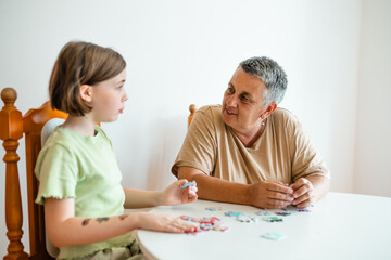 Grandmother and granddaughter doing puzzle at home.