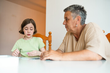Grandmother and granddaughter doing puzzle at home.