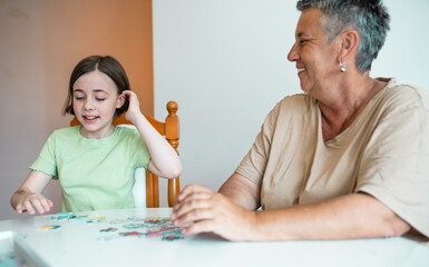 Grandmother and granddaughter doing puzzle at home.