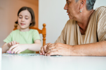 Grandmother and granddaughter doing puzzle at home.