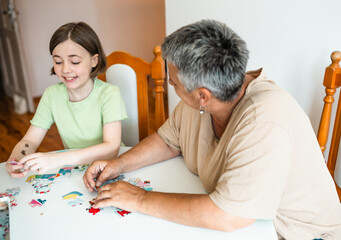 Grandmother and granddaughter doing puzzle at home.