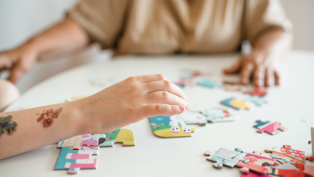 Grandmother and granddaughter doing puzzle at home. - Powered by Adobe