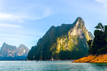 Front view of a bright blue morning sky with clear white clouds. The water is deep indigo in...