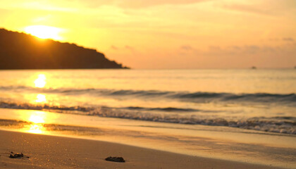 Obraz premium A serene sunset over a beach, casting golden hues on the water and sand, creating a tranquil atmosphere perfect for relaxation