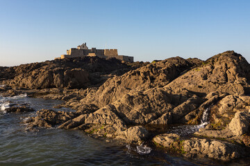 Fort National in Saint-Malo at low tide with rocky coast and evening sunlight