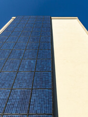 Vertical solar panels on urban building facade under clear blue sky – sustainable city energy concept