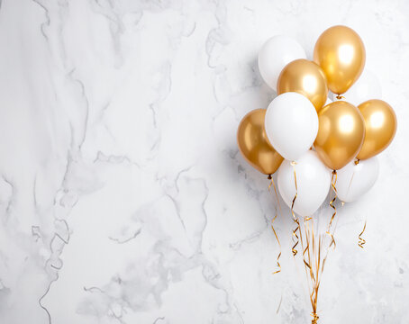 Globos dorados y blancos con cintas sobre fondo de m&aacute;rmol claro