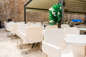 Outdoor cafe terrace with white chairs and floral decor. Hospitality atmosphere, modern leisure space, and Mediterranean dining culture.