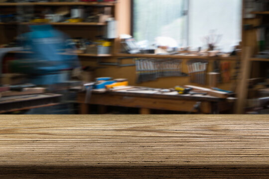 Crafting tools and wooden surfaces in a busy workshop during the day with a blurred background of activity