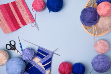 Needlework set of blue and pink balls of knitting thread, knitted striped future scarves with...