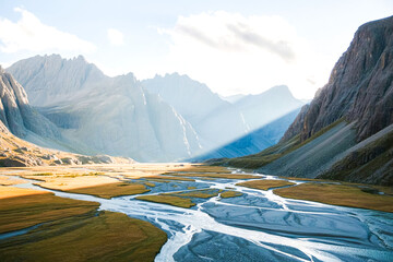 Sunbeams illuminate serene mountain valley river landscape