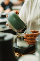 Hands pouring Japanese roasted tea for Hojicha Latte