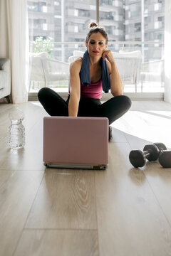 Woman training at home with laptop and weights