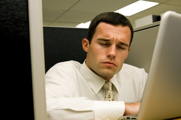 Stressed Businessman at Work in Office Cubicle with Laptop
