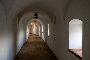 Long white arched monastery corridor with tiled floor and soft light, peaceful sacred architecture