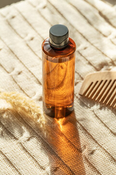 Hair care oil bottle in sunlight on a textured surface