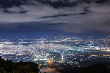 Aerial view of city skyline landscape at night with misty clouds over the illuminated cityscape...