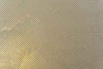 Water streams down glass covered with metal mesh, catching light and texture. The effect is cool, modern, and quietly captivating.