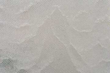 Water streams down glass covered with metal mesh, catching light and texture. The effect is cool, modern, and quietly captivating.