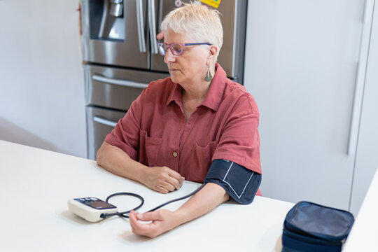 Elderly woman checking blood pressure at home