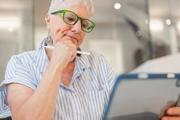 Elderly woman using tablet at home for technology learning