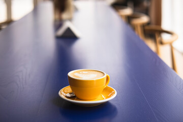 Yellow coffee cup on blue table in cafe setting