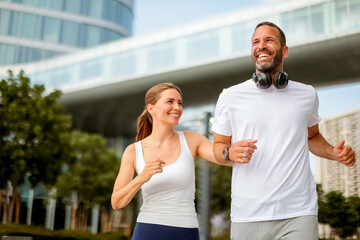 Joyful couple enjoying a morning run in a modern cityscape surrounded by lush greenery