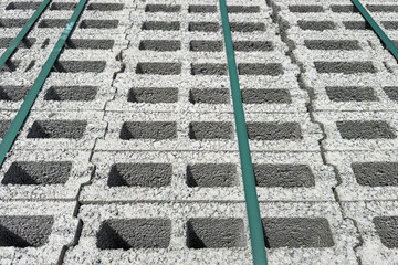 Concrete breeze blocks in stack with green packing straps, construction material background