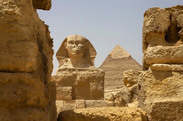 The Great Sphinx sits majestically against a pyramid in the background, showcasing the rich history...