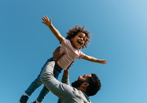 Joyful Black father lifting daughter outside, playful family bonding, happy child flying in air under blue sky, carefree childhood, positive parenting moment in nature