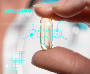 Transparent pill held between fingers with medical symbols in a clinical setting during daytime