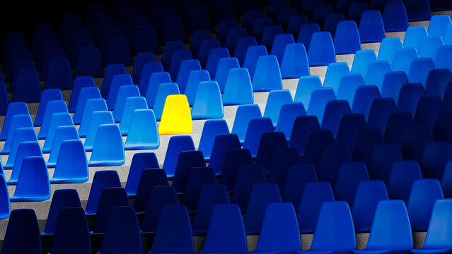 Bright yellow stadium seat stands out among blue chairs in isolation