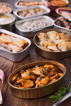 Assorted canned seafood variety on wooden table